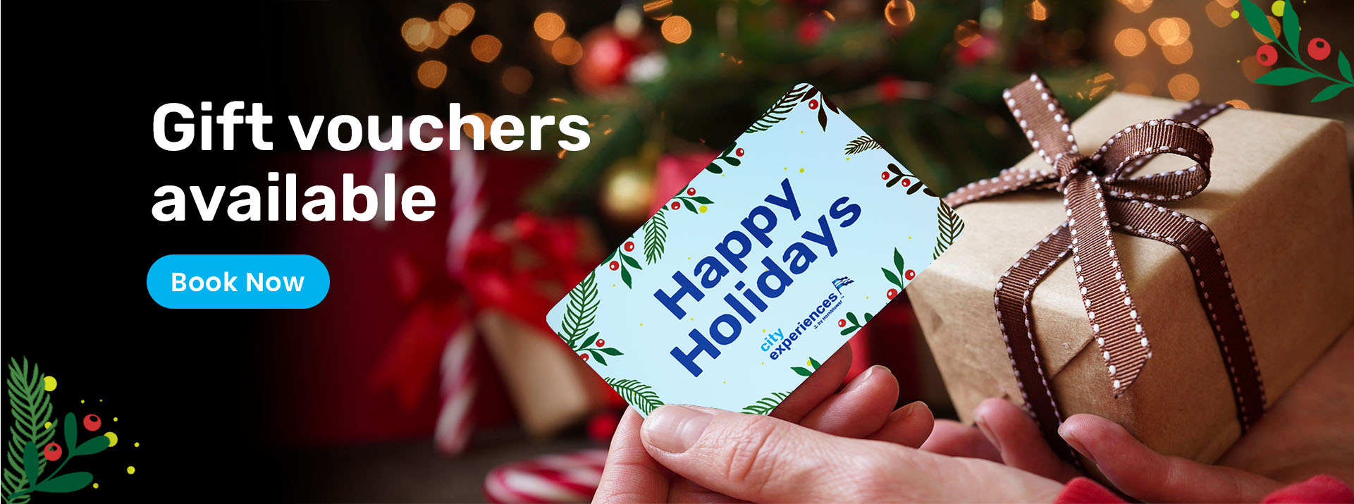 2021_308000_CC_UK_WEB-Holiday Sliders Sales Artwork-Giftvouchers-Final Hands holding a blue holiday gift voucher and brown paper wrapped gift with candy canes and holiday lights in background.
