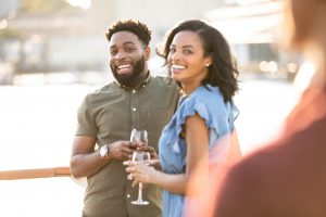 Couple drinking wine and smiling on the deck of a boat.