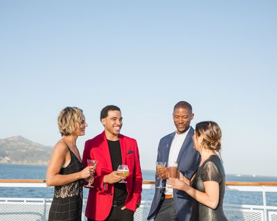 Two couples on boat talking holding drinks.