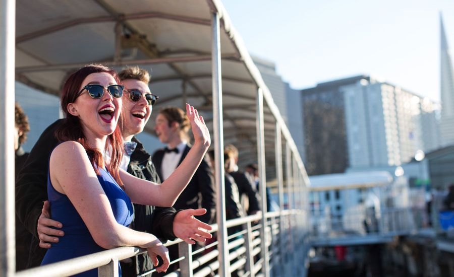 Couple waving from railing of boat.