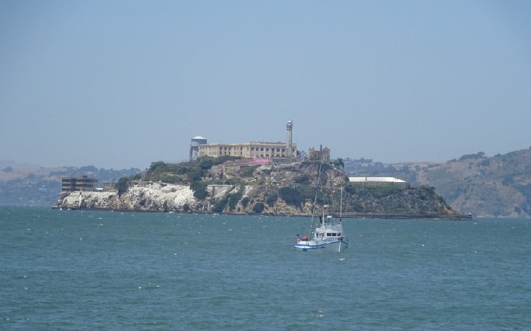 Alcatraz Island katika umbali mashua ndogo katika mbele