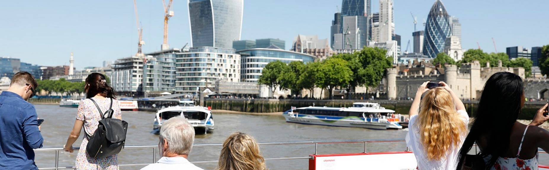 Folk på båddæk på Themsen og London i baggrunden