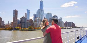 一对夫妇在秋天的落叶和纽约市天际线的背景下拥抱在一起。