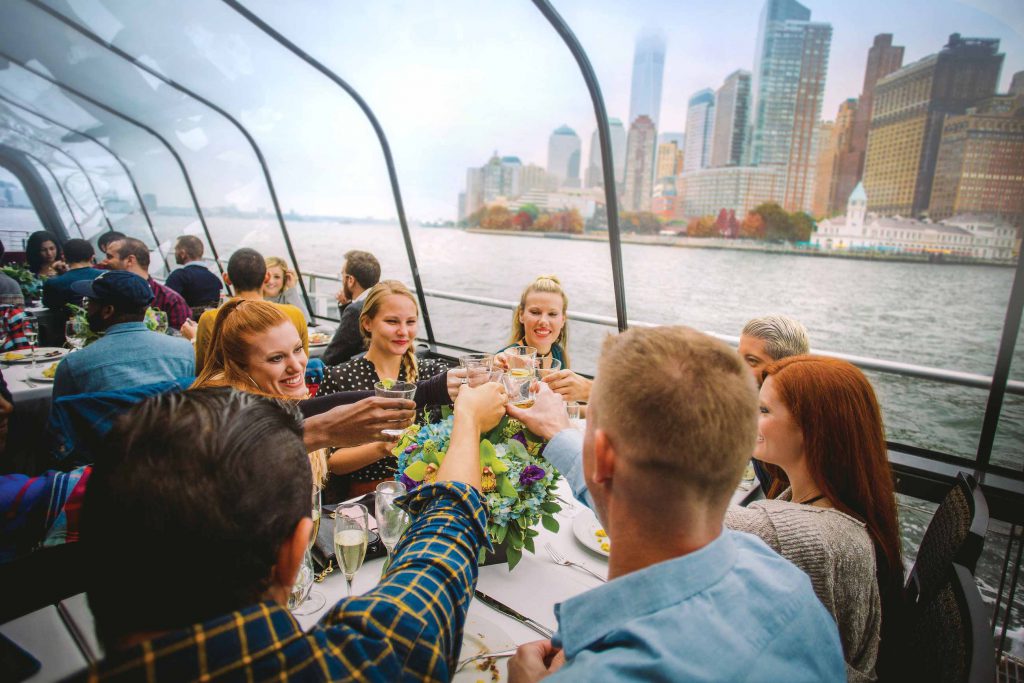 人們在以秋葉和紐約市天際線為背景的Bateaux上歡呼。