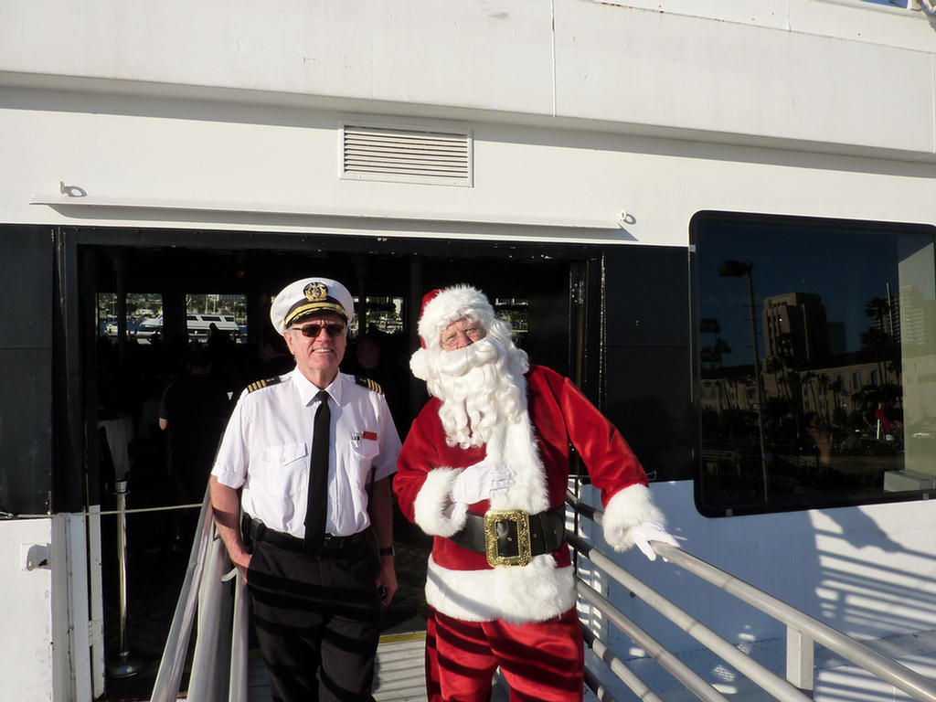 Julemanden og kaptajnen på krydstogtskibet står ved siden af båden