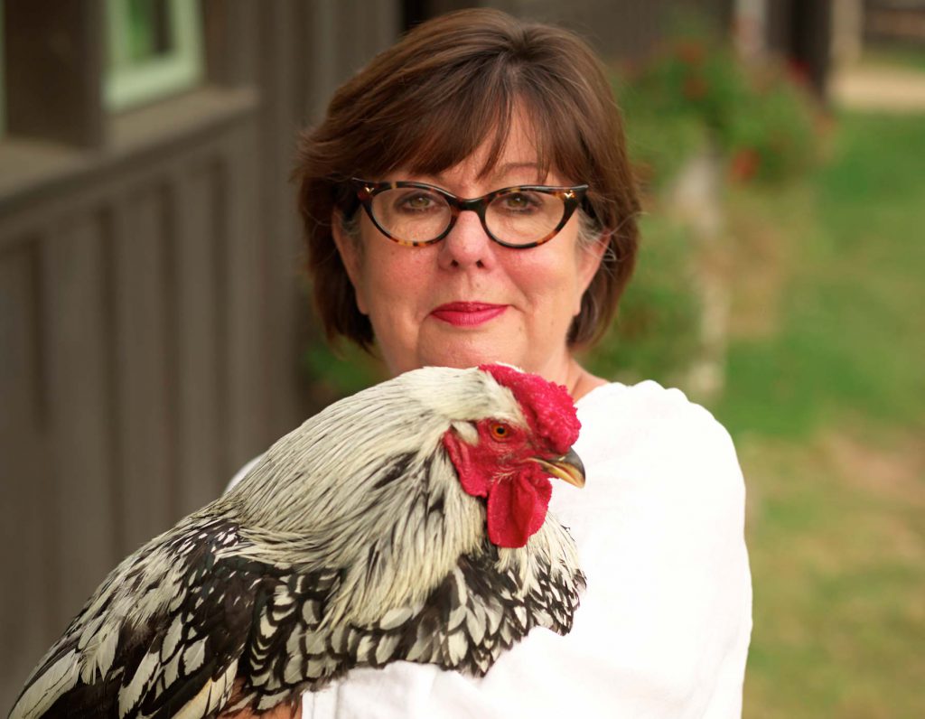 Regina Charboneau con in mano un pollo.