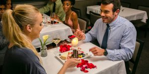 Couple eating dessert with rose petals on table.