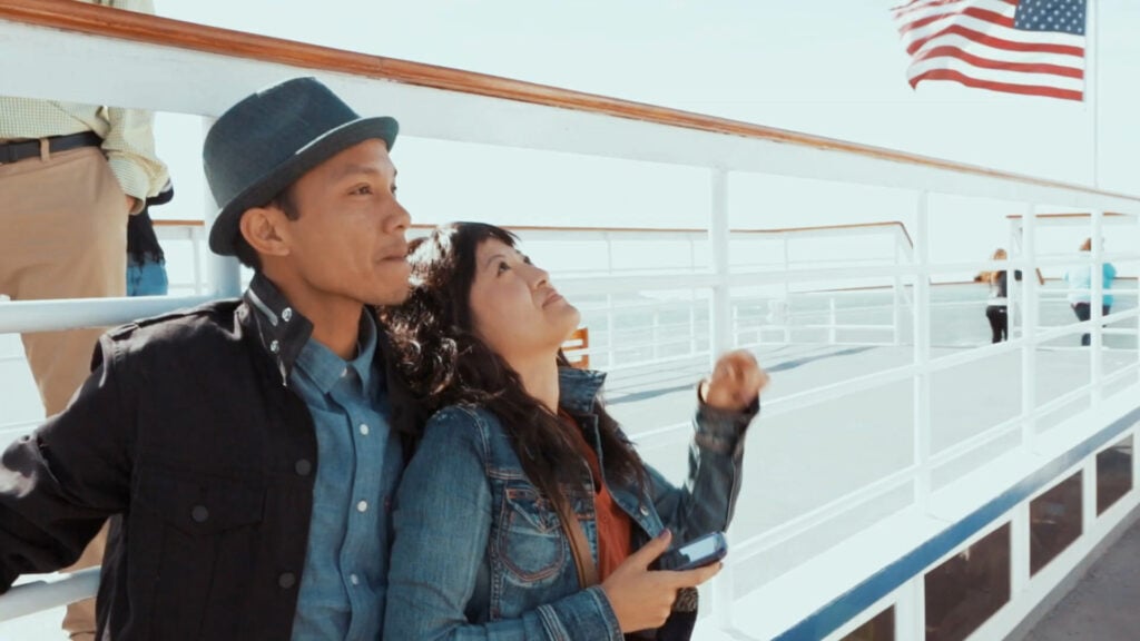 Couple on ship in San Francisco with American flag in background