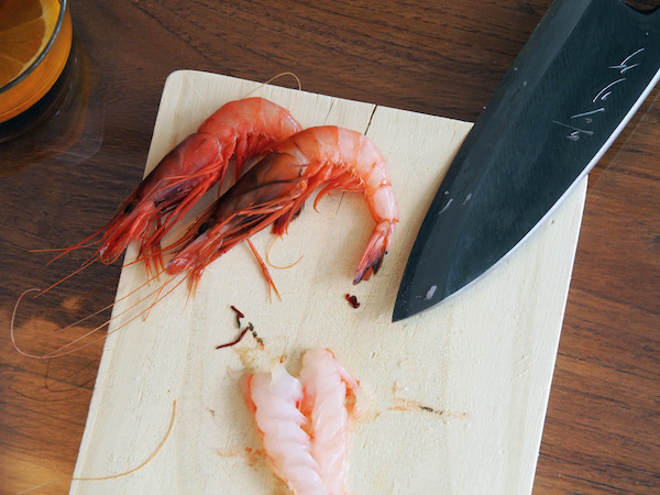 Crevettes sur une planche à découper avec un couteau en acier noir