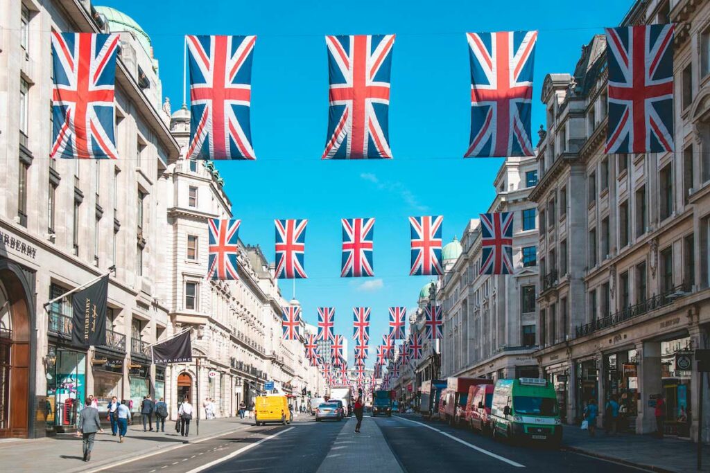 Rua em Inglaterra com bandeiras do Union Jack drapeadas entre edifícios.