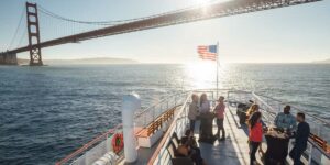 Orang ramai haluan bot dengan Jambatan Golden Gate di latar belakang