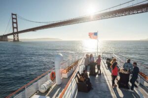 Mensen op boeg van boot met Golden Gate Bridge op achtergrond