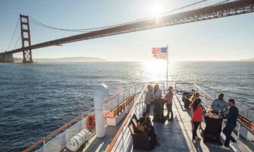 Menschen am Bug eines Bootes mit der Golden Gate Bridge im Hintergrund