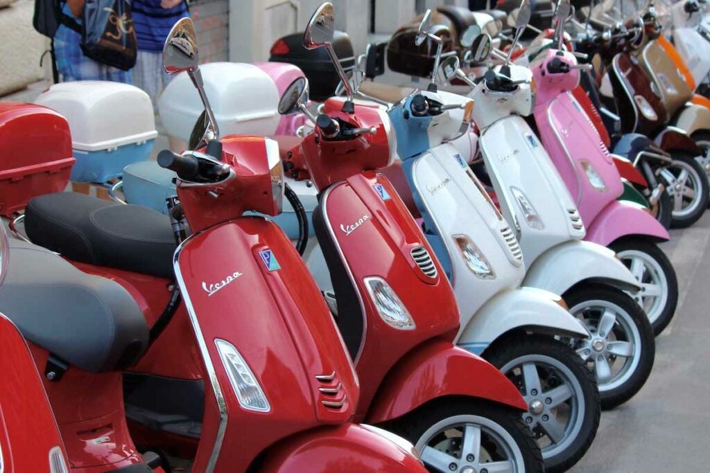 Arka arkaya dizilmiş renkli Vespa motorlu scooter.
