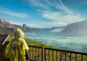 Person in gelben Ponchos, die die Niagarafälle aus der Ferne betrachtet.