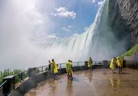 People in yellow ponchos viewing Niagara Falls from beneath.