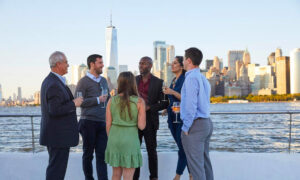 Gente de pie en la cubierta del barco con el horizonte de Nueva York en el fondo