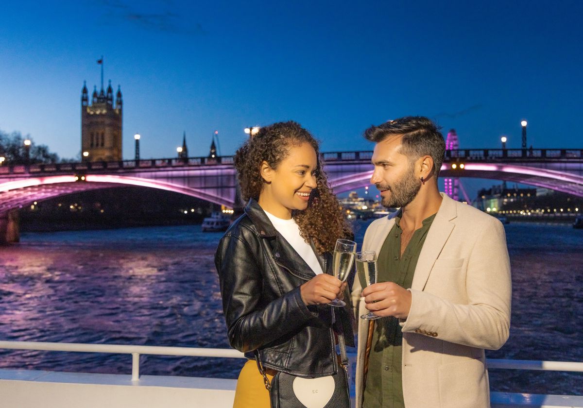 Couple cheering Champagne in London with bridge in background