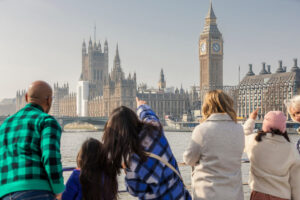 लंदन, इंग्लैंड में वेस्टमिंस्टर और बिग बेन के महल को देखते लोग।