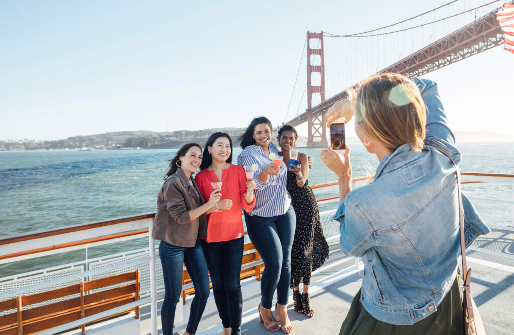 group standing for a picture in front of san francisco bridge on a boat