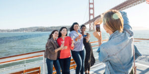 group standing for a picture in front of san francisco bridge on a boat