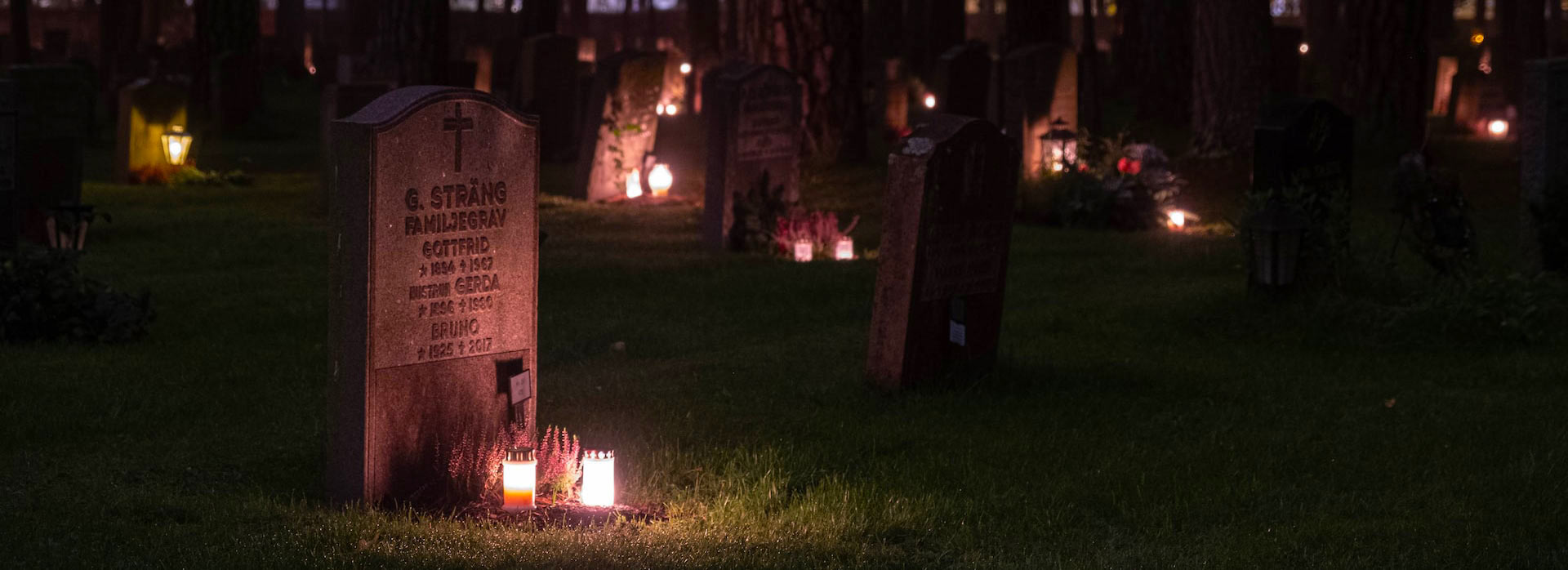 A graveyard at night lit with candles