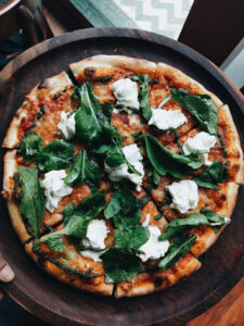 Una pizza su un piatto di legno