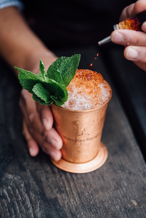 Drink being made in a copper cup with mint and ice.