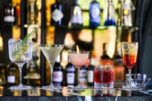 Multiple colorful cocktails on a bar