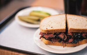 Un sandwich au pastrami accompagné de cornichons