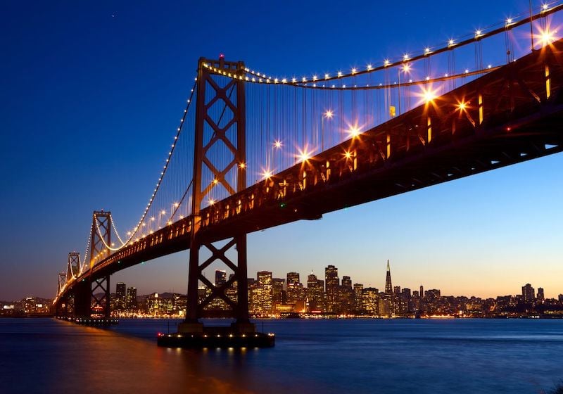 San Francisco - Oakland Bay Bridge om natten oplyst