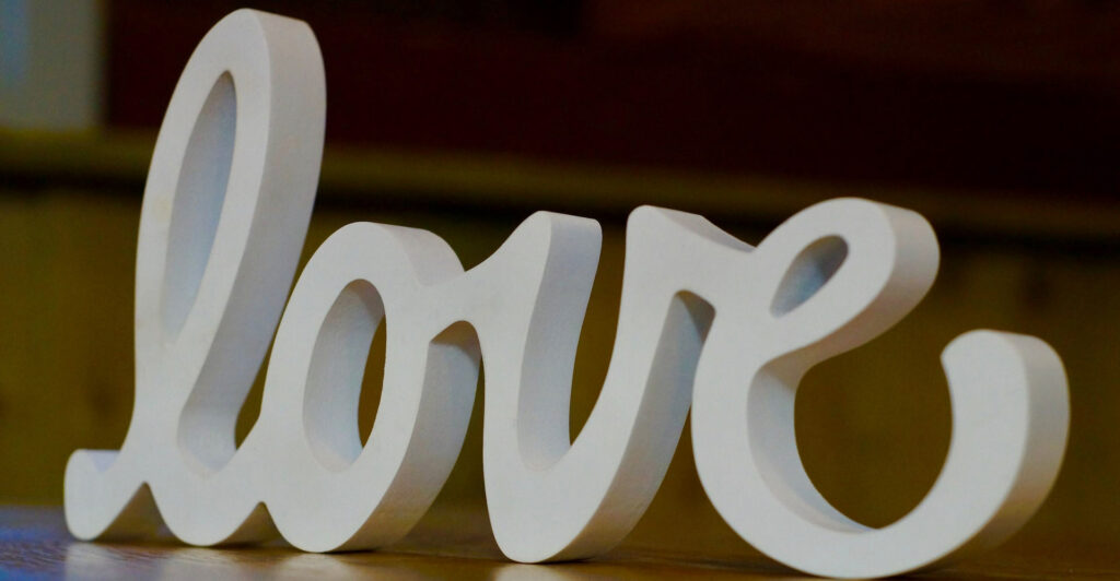 प्रेम शब्द को एक मूर्तिकला के रूप में कर्सिव में लिखा गया है