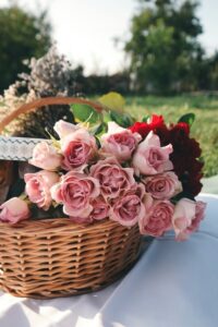 A basket of flowers on a white cloth under green grass