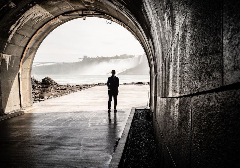 Een persoon kijkt uit op de Niagara watervallen vanuit een tunnel op waterniveau.