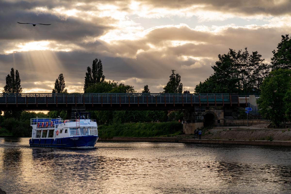 bateau yorkais naviguant sous un pont au coucher du soleil