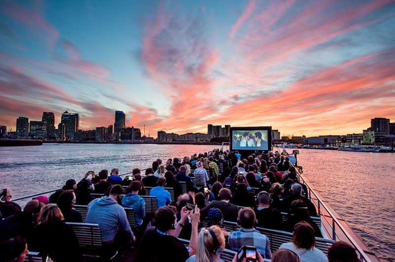 gente viendo películas en el río en un barco de cruceros urbanos