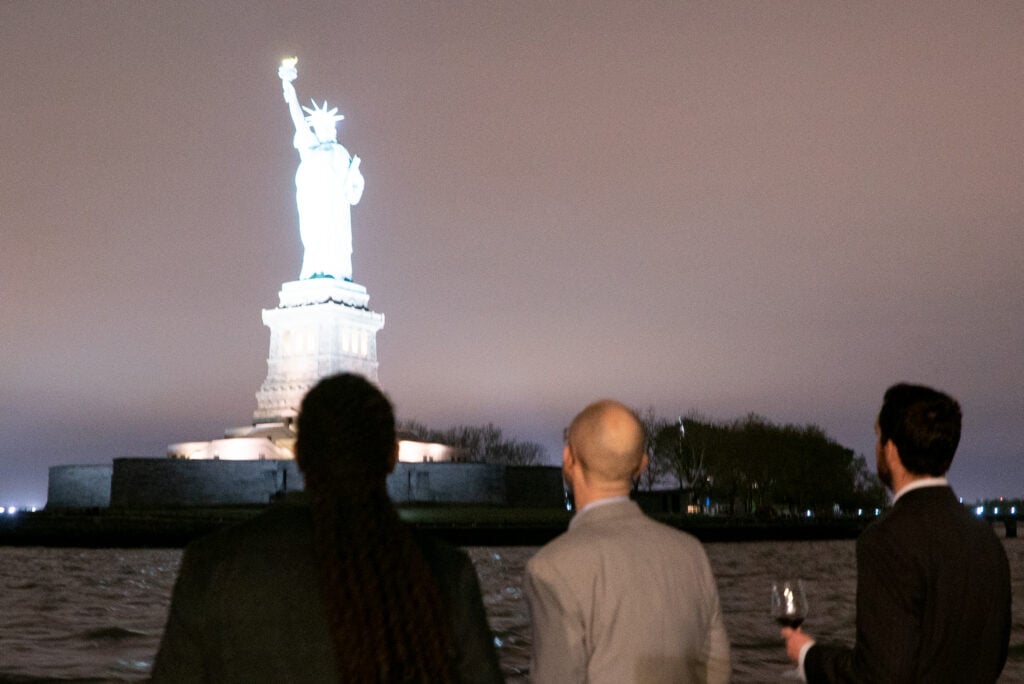group looking at statue of liberty at night
