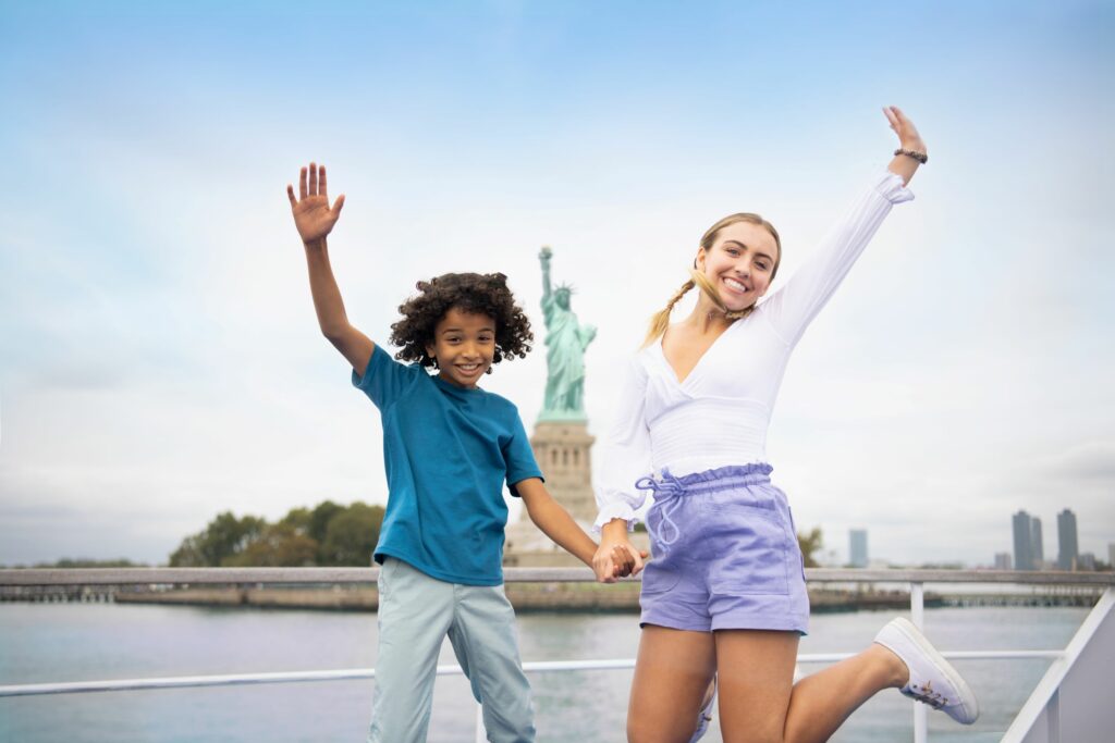 boy and girl jumping in front of statue of liberty