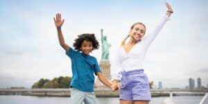 boy and girl jumping in front of statue of liberty