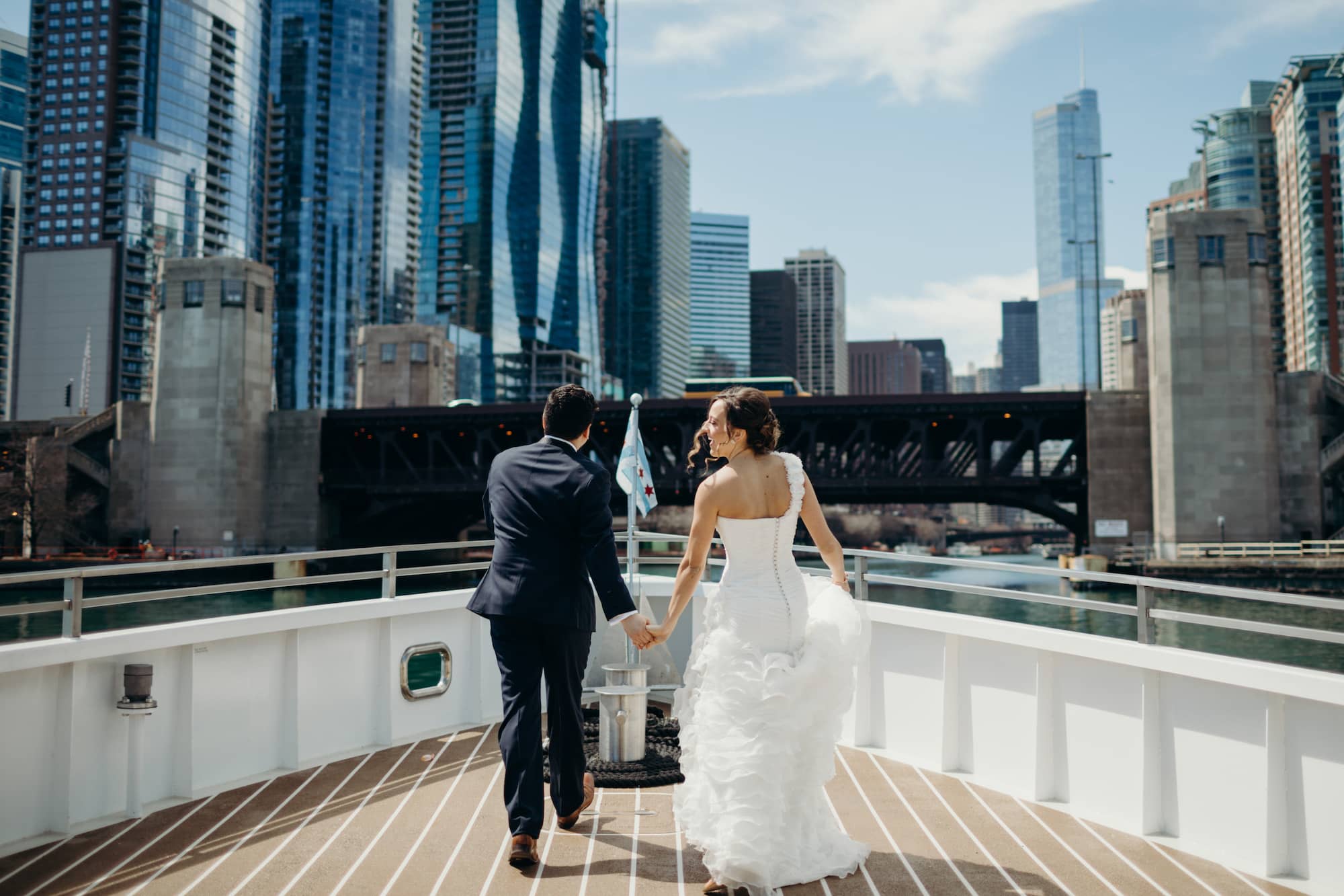 Married couple on bow of boat on Chicago river with buildings in background